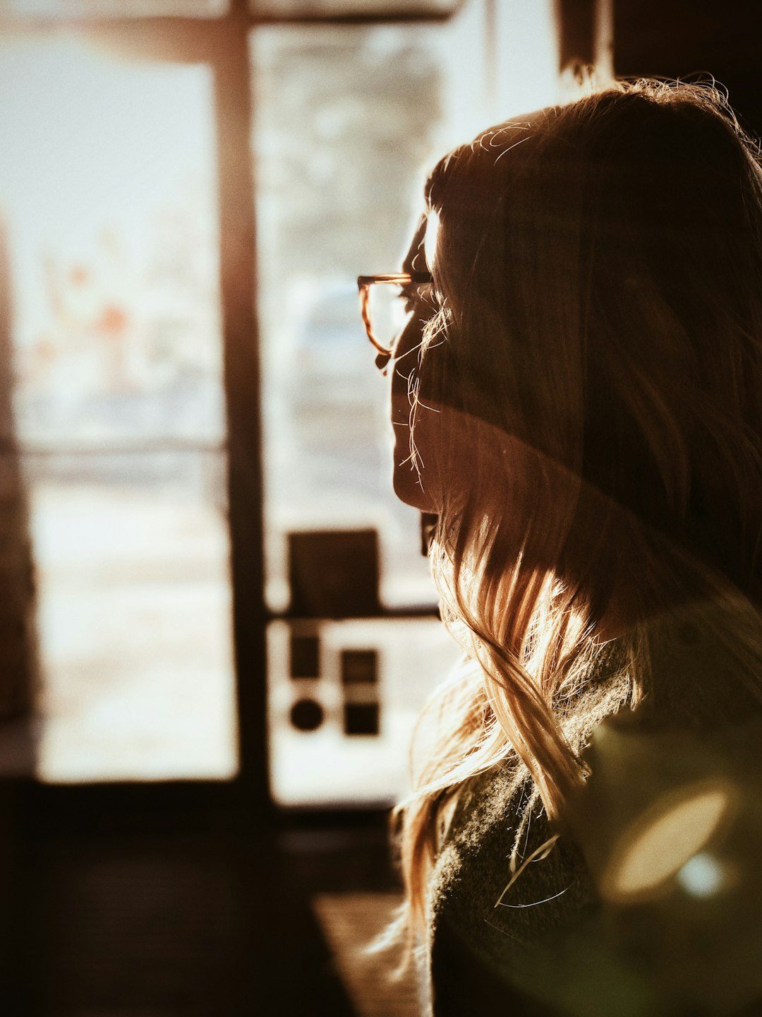 A woman in a quiet, reflective moment by a softly lit doorway